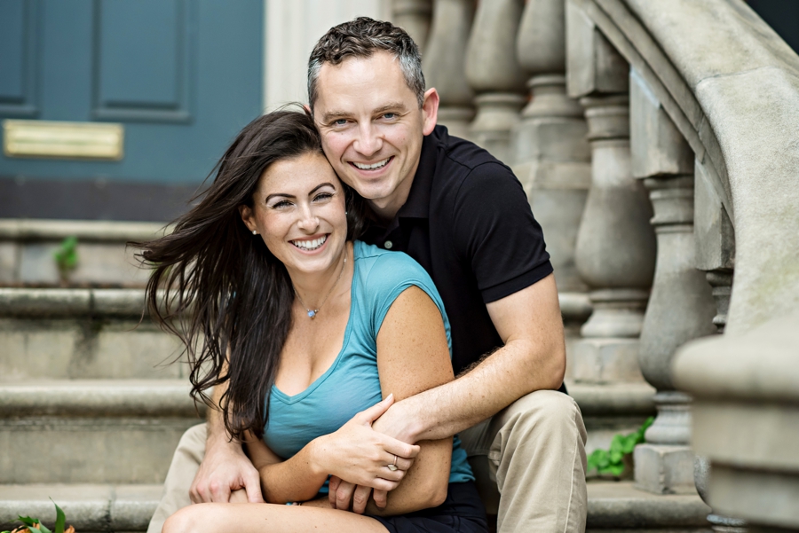 An engaged couple on a rittenhouse square steps with wind blowing.
